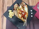 Dorada abierta a la plancha con ajos, pimiento rojo y limón sobre una pizarra