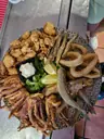 Fuente de fritura con calamares, boquerones, chopitos y sepia alrededor de un cuenco de alioli