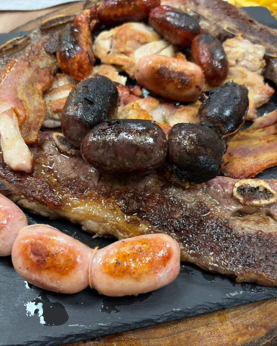 Parrillada de carnes con chorizos, morcillas, salchichas, panceta y carne a la brasa sobre una tabla