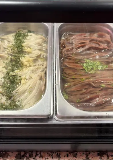 Dos bandejas de pescado en vinagre y en aceite en la vitrina