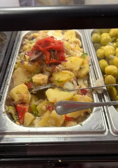 Patatas aliñadas con pimiento rojo junto a una bandeja de aceitunas